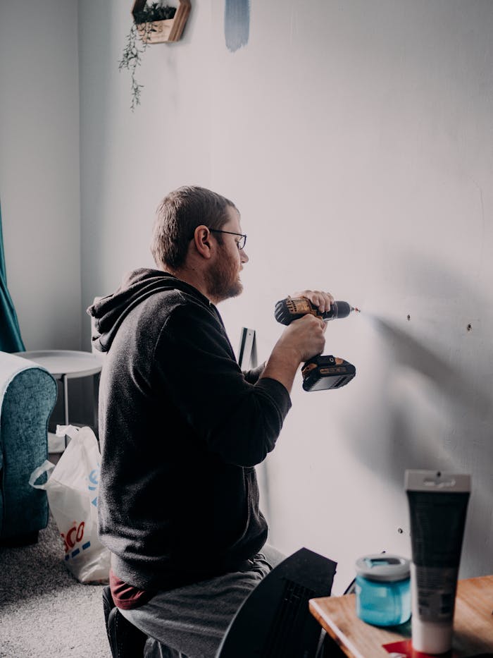 Home Adult man using a power drill indoors for home improvement in a well-lit room.