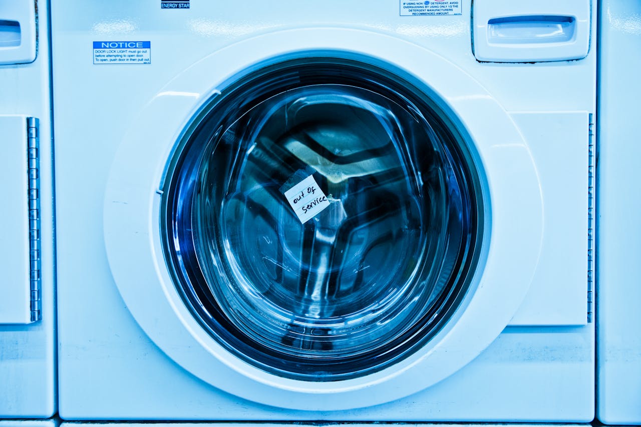 About Close-up of an out-of-service washing machine in a laundromat with a blue tint.